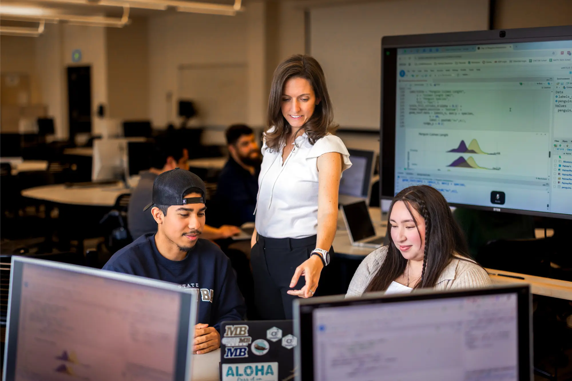 Dr. U assisting two students with statistics in a classroom setting