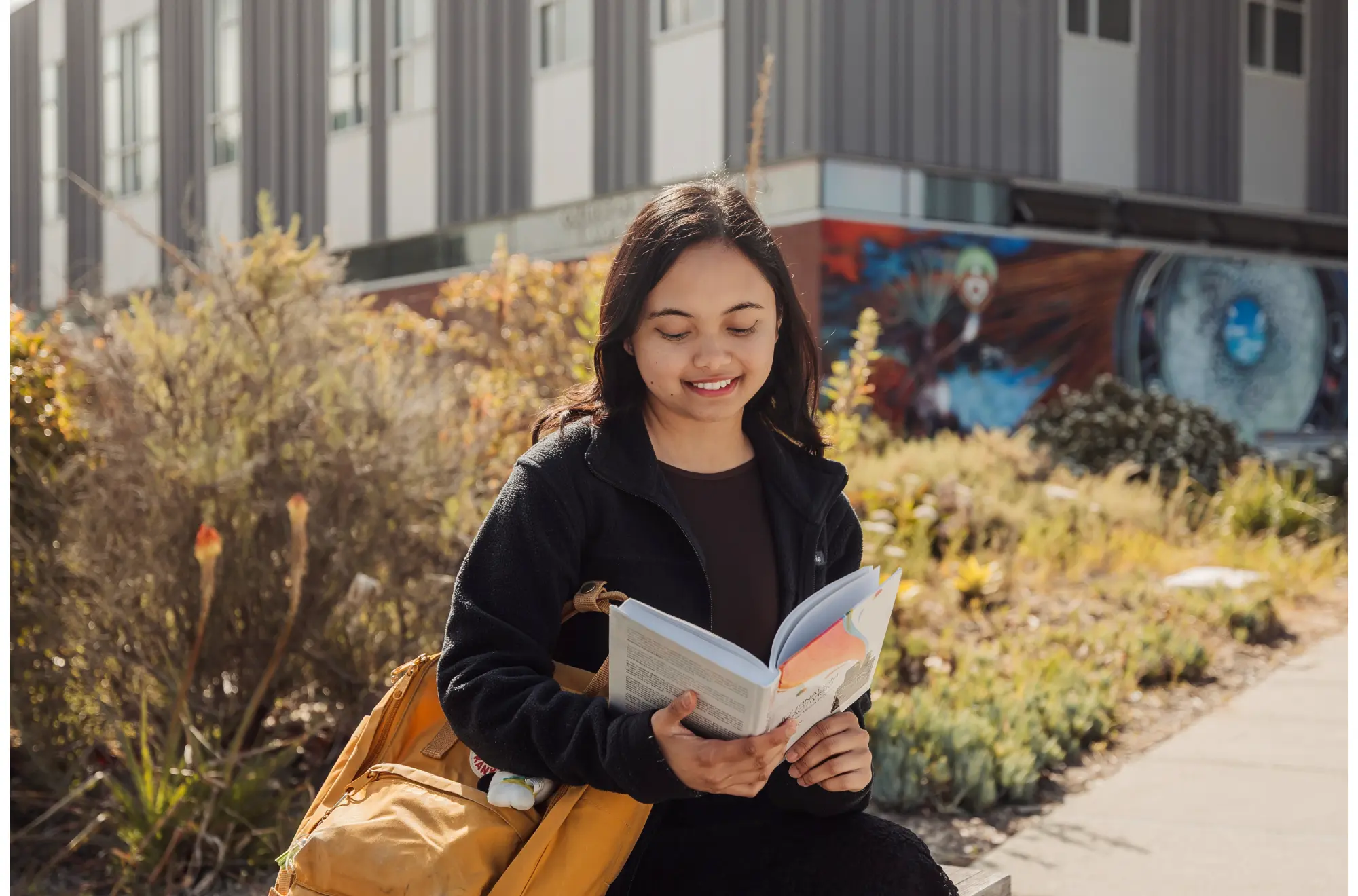 A student sitting outside reading a book.