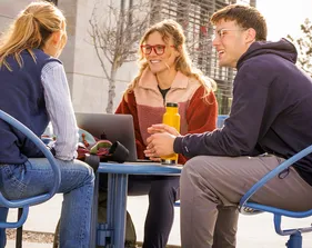 Three students sitting at a table and talking