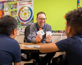 Teacher and students sitting at a table learning shapes and numbers laughing