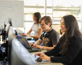 A group of students working on their laptops in the business and information technology building