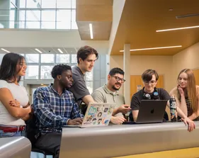 Group of students collaborating on a computer in the Business and Information Science building.
