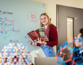 A statistics student writing on a whiteboard