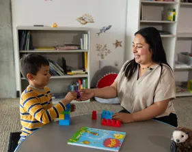 Student giving a child a toy building block.