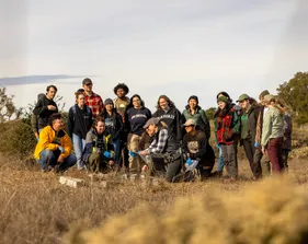 A group of AES students look at their professor taking a field mouse out of a bag.