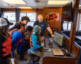 A group of four students and a professor working on a computer