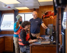 A group of two students and a professor working on a computer