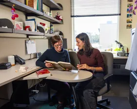 Professor and student read a book in the professors office