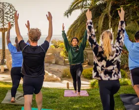 Students participating in a yoga session by the sea