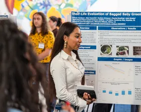 A student presenter stands in front of their graphic