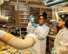 Two marine science students work in a lab while one holds a beaker