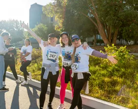 Two runners high-five as they cross the finish line, smiling after their 5K run.