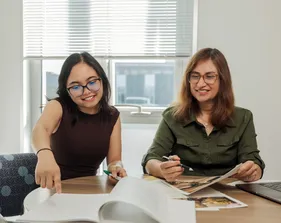 Student and Professor sitting at a table looking at a paper together