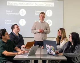 A business administration student giving a presentation to four others