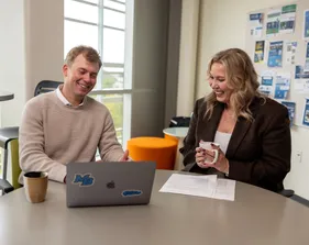 A business administration student and professor sitting down and collaborating together