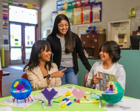 A social work credential student in a classroom teaching two kids