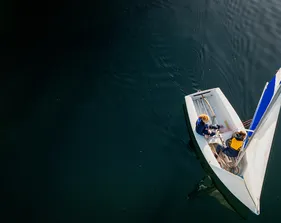 Two students sail on calm water, engaging in hands-on coastal learning and teamwork.