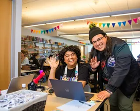 Students smiling and waving in the maker space