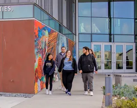 Group of students walking out of a building together on campus.