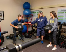 Students with teacher in gym lifting weights