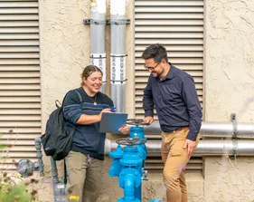 A CSUMB environmental studies student and faculty member review field notes together while examining campus utility infrastructure as part of a hands-on research activity.