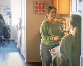 Students chatting while cooking together in a kitchen