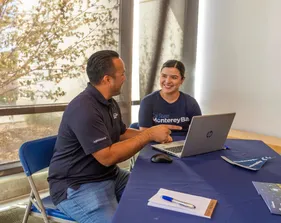 Two students sitting at a table with a laptop