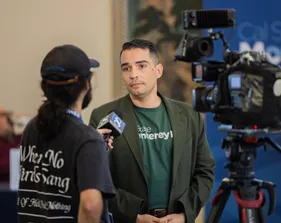 A news crew member interviewing a faculty member and recording it.