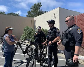 The CSUMB University Police Bike Patrol talk with a civilian on campus while standing with their bikes.
