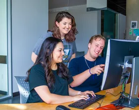 Three students using the computer at the library