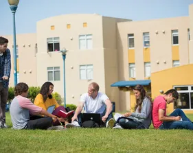Five students sitting on the CSUMB Quad and one student holding his bike