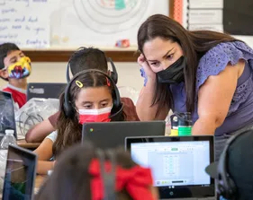 Photo: CSUMB student and co-teacher Gabriela Suarez answers a student’s question during a math lesson.