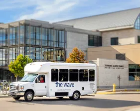 The Wave shuttle driving in front of the library.