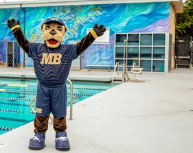 Mascot posing beside swimming pool