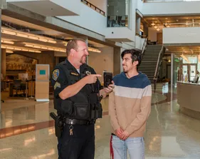 A UPD officer showing showing his phone to a student