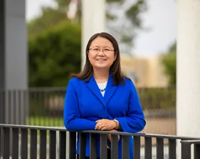 Yimin Wang standing by a fence
