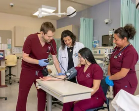 A group of three students and a professor doing a demonstration on how to use equipment