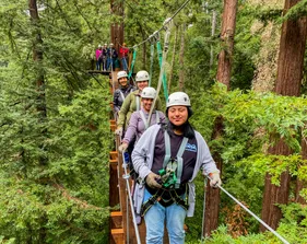 Students crossing a rope bridge with safety gear in place