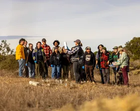 A group of people standing in the field and discussing