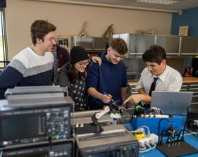 Four students working together on electric board