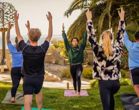 Students participating in a yoga session by the sea