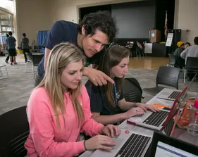 Two people on laptop with student helping them