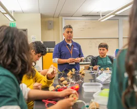 An instructor guiding a small group of students as they work on hands-on project.