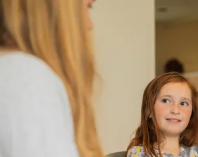 A child engages in a learning activity with guidance from an adult, highlighting a supportive and interactive educational environment.