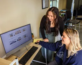 Student helping another student at a computer