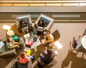 Students are sitting around the table in the library space