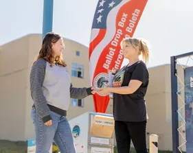 People chatting beside a flag on campus