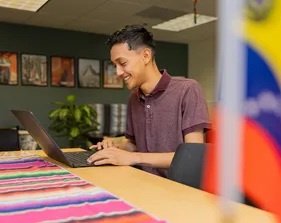 Student typing on a laptop inside El Centro.