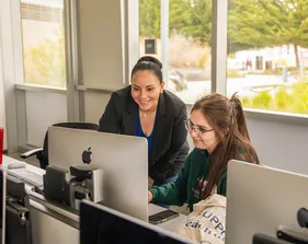 Professor helping a student at her desk in a classroom