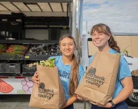 Two students holding bags of produce from the produce truck.